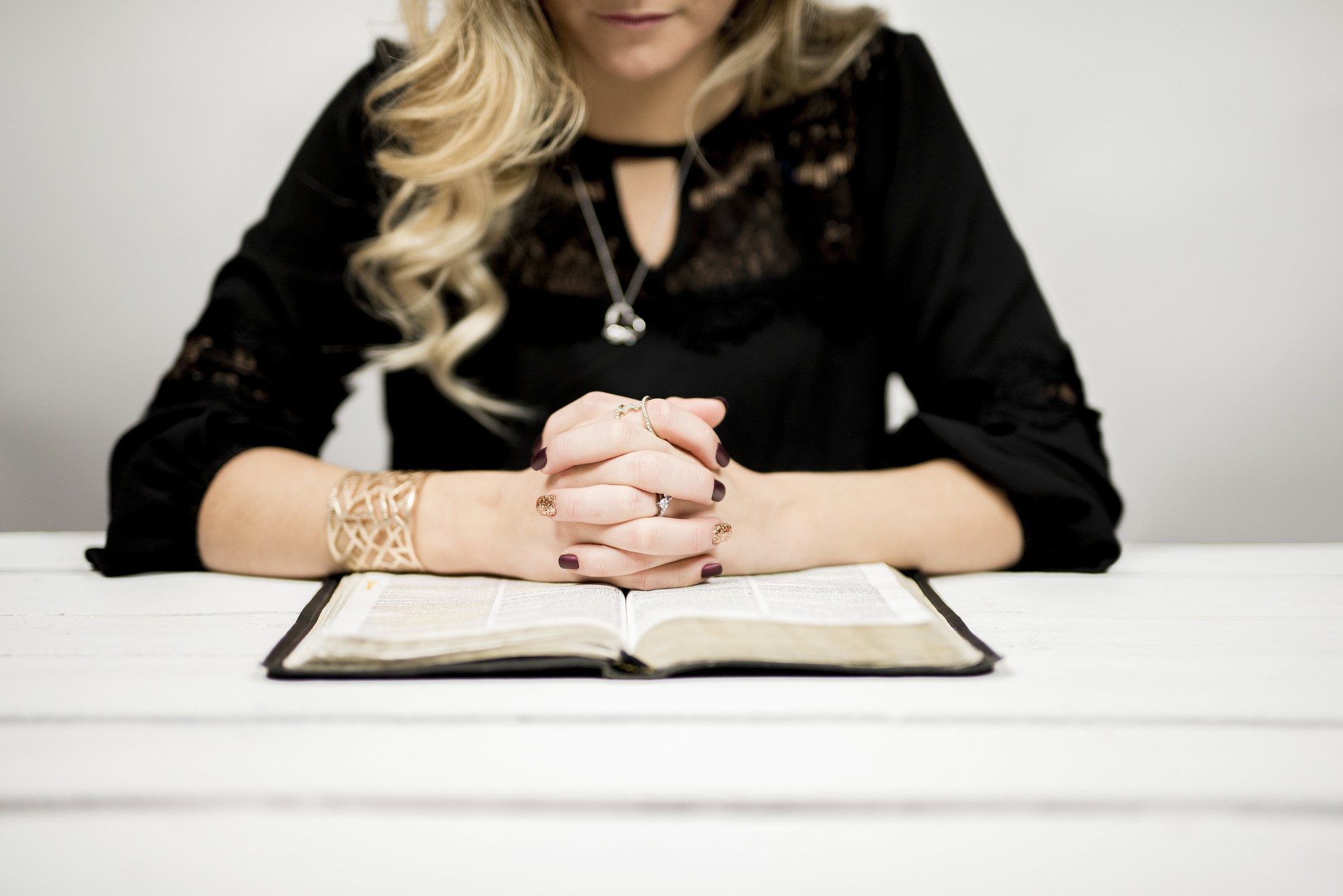 Woman praying with an open bible | Most Holy Eucharist